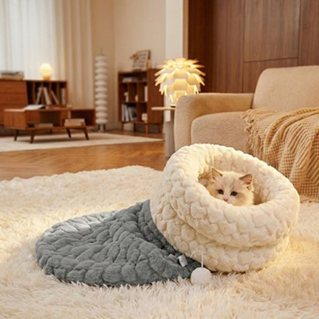 Chaton allongé paisiblement dans un lit chaton posé sur un tapis blanc