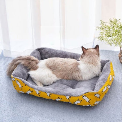Un chat  à poils long allongé dans un panier chat rectangulaire et moelleux 