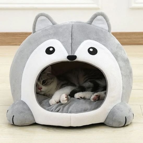Chat tigré gris et blanc allongé confortablement dans un panier pour chat en peluche grise