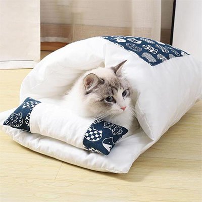 Chat allongé dans un lit pour chat blanc et bleu avec motif de chats