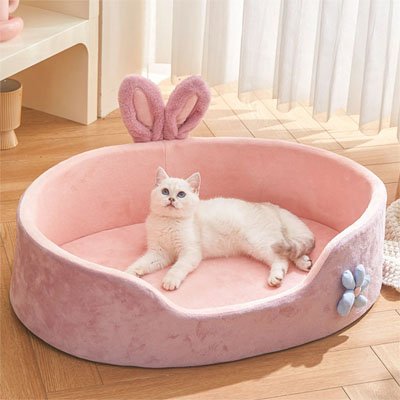 Chat blanc allongé confortablement dans un panier chat en peluche rose et mauve 