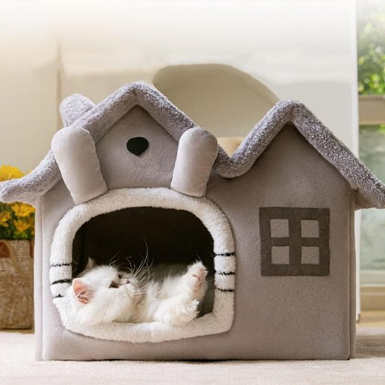 Chat blanc allongé paisiblement dans un Panier pour chat en forme de petite maison 