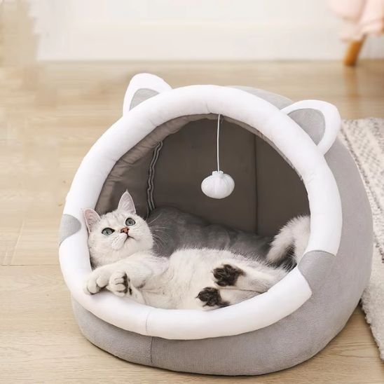 Chat blanc allongé sur le dos à l'intérieur d'un panier pour chat arrondi en forme de tête de chat 