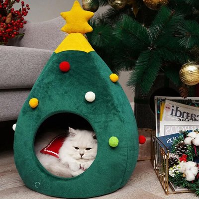 Chat blanc est allongé à l'intérieur d'une niche pour chat en forme de sapin de Noël vert