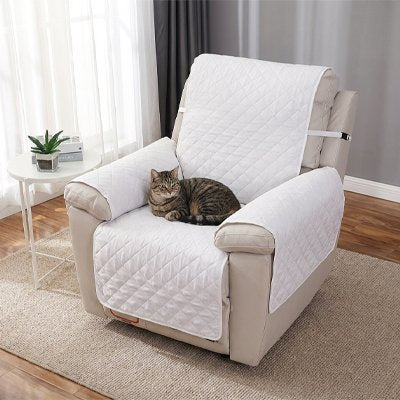 Un chat tigré est couché sur un fauteuil beige protégé par une protection canapé chat 