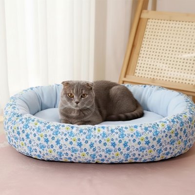 Chat gris assis calmement dans un coussin pour chat à motif floral