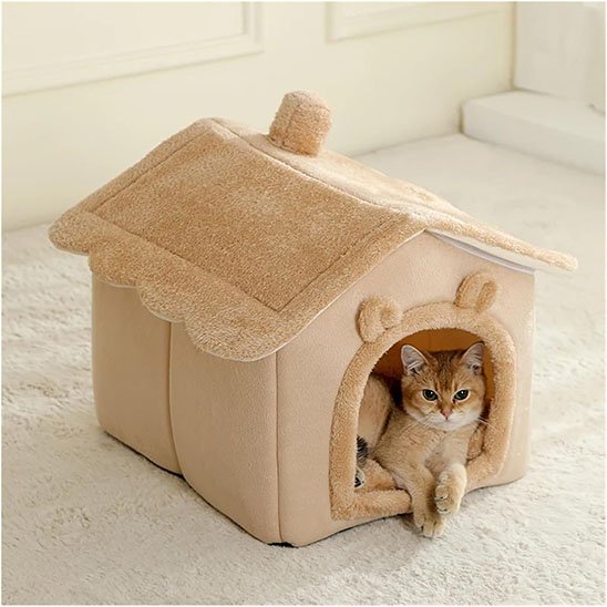 Chat roux couché à l'intérieur d'une niche pour chat en peluche marron