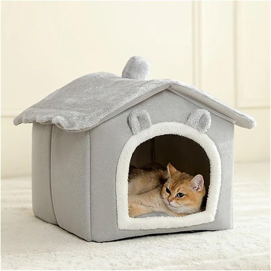 Chat roux couché à l'intérieur d'une niche pour chat en peluche grise