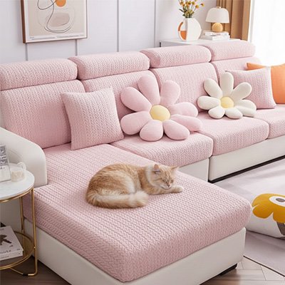 Un chat roux et blanc dort sur un grand canapé équipé de protection canapé chat rose texturée et décoré de coussins en forme de fleurs