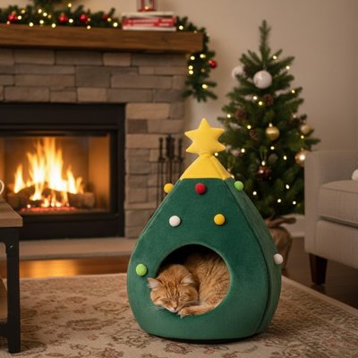 Chat roux endormi à l'intérieur d'une niche pour chat en forme de sapin de Noël vert