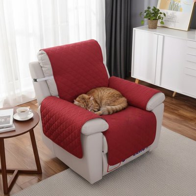 Un chat roux endormi sur une protection canapé chat de couleur bordeaux du fauteuil inclinable beige 