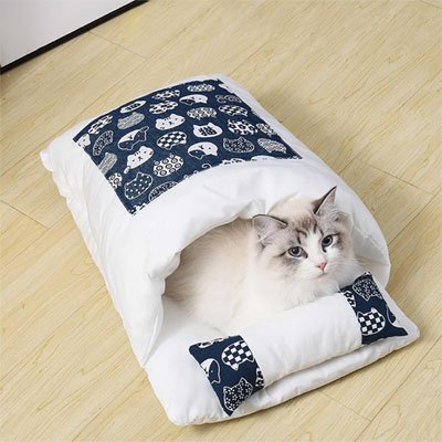 Chat se reposant dans un lit pour chat blanc et bleu avec motif de chats