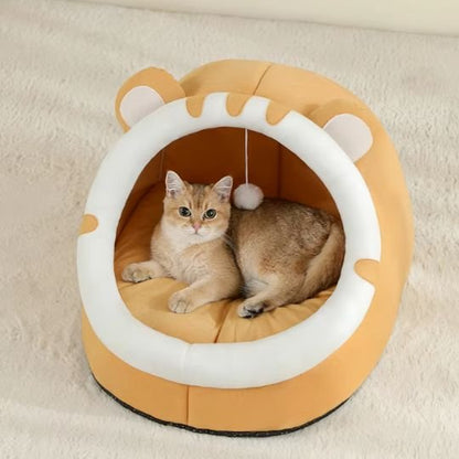 Chat tigré assis confortablement dans un lit chaton de couleur orange