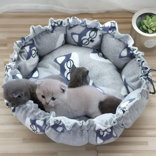 Trois chatons gris et beiges installés confortablement dans un coussin à chat de couleur gris