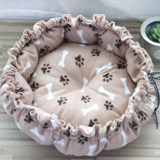 Coussin à chat beige lavable et moelleux, avec motifs ludiques de pattes et d'os.