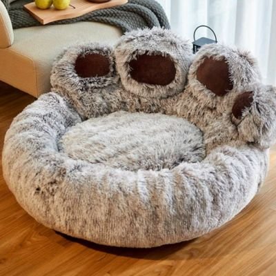 Un coussin pour chat en forme de patte de chat géante, en peluche grise et douce.
