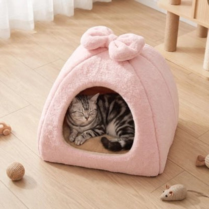 Maison pour chat de couleur rose sur plancher en bois