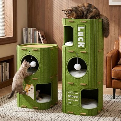 Trois chats jouant et se reposant sur  niche pour chat  cylindrique verte de hauteurs différentes.
