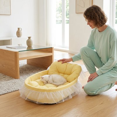 Une femme est agenouillée sur un plancher en bois et veille sur un chaton blanc endormi dans lit pour chats 