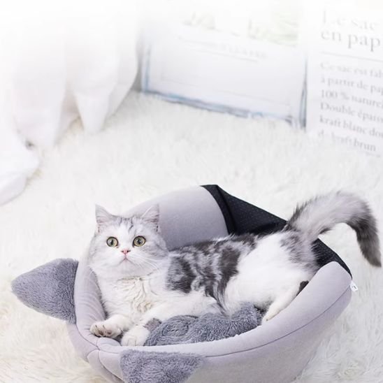 Un chat blanc et gris est couché dans un panier chat gris en tissu souple