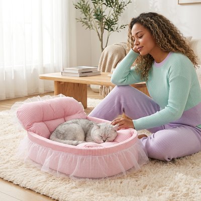 Une femme regarde avec tendresse un chat blanc et gris endormi dans lit pour chats 