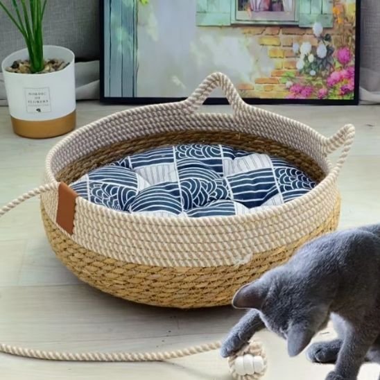 Un chat noir joue avec la corde d'un lit pour chat