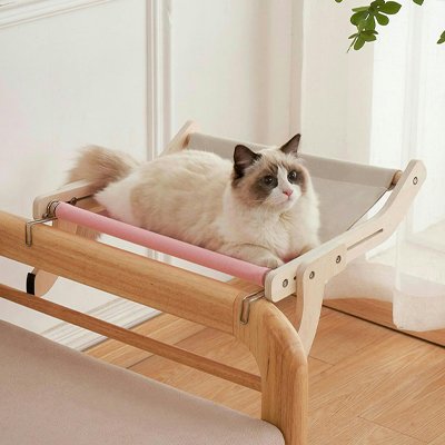Un chat bicolore à poil long est confortablement installé sur un hamac pour chat surélevé