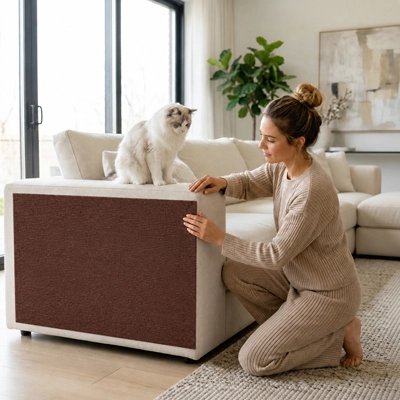 Une femme applique une housse de canapé anti griffe de chat de couleur marron 