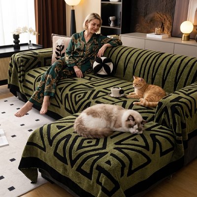 Une femme assise sur un canapé recouvert d’un protege canape chat vert à motifs géométriques se détend en compagnie de deux chats