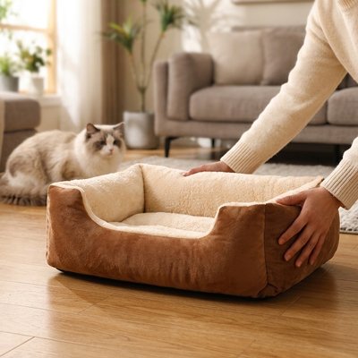Une femme prépare le panier chat rectangulaire marron et crème devant son chat